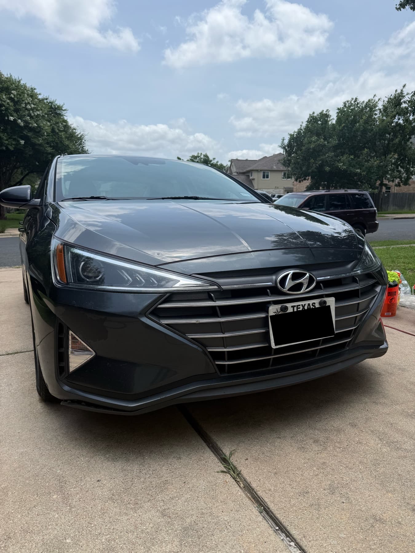 Freshly detailed sedan front end in a driveway